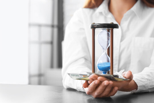 Businesswoman with hourglass and money in office, closeup