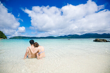 couple cuddling on the beach and the blue sea with the blue sky background,The happiness of the newly married couple
