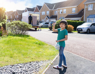 Fototapeta premium Full lenght portrait happy Kid carrying bucket of colourful chalks, Active boy playing outdoor in sunnyday summer, New normal life child playing around home street area while Covid-19 Quarantine