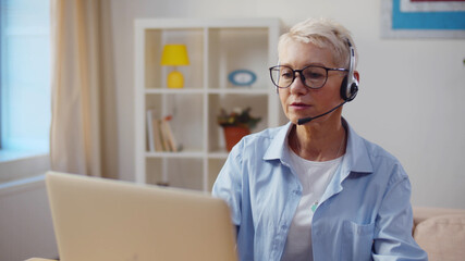 Active senior woman working at home office on laptop