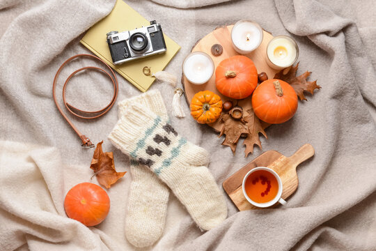 Beautiful autumn composition with knitted socks, cup of tea and photo camera on plaid