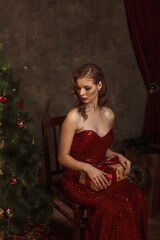 The glamorous model in a red dress posed on a vintage New Year's background.
