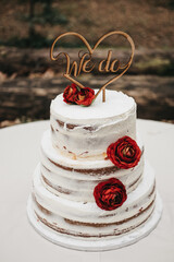 Obraz na płótnie Canvas Vertical shot of a white gourmet wedding cake with red flowers