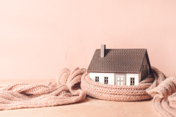 Figure of house and warm scarf on table. Concept of heating season