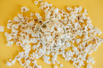 Popcorn in paper cup on a yellow background. Top view. Copy, empty space for text