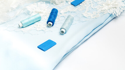 Tailoring concept. beautiful white guipure and blue satin fabric with thread and chalk on a white background. Top view. flat lay