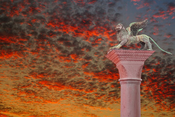 Ancient top tower sculpture of symbol of Venice winged lion at the Piazza San Marco at bloody red...