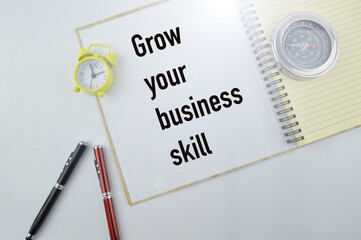 Selective focus of pens, compass, clock and notebook written with GROW YOUR BUSINESS SKILL. Business concept.