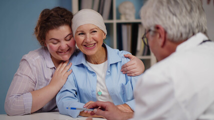 Cancer patient woman visiting doctor with daughter and smiling hearing good news