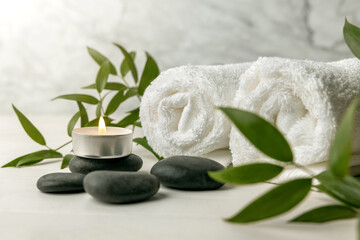spa stones with white towels, burning candle and green plant