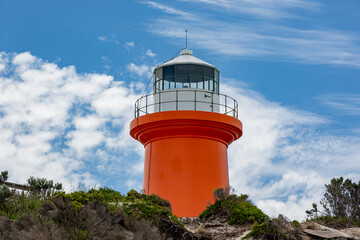 The iconic red Cape banks lighthouse with blue sky and white clouds located at Carpenters Rocks...