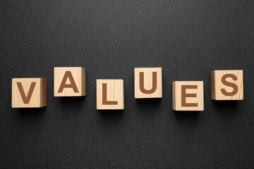 Obraz premium Wooden cubes with word VALUES on black background, flat lay