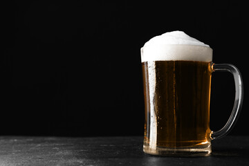 Cold tasty beer on grey table against dark background. Space for text