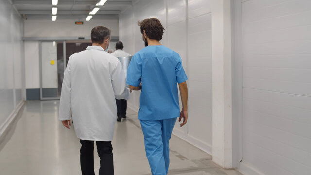 Back view of doctor and surgeon discussing lings x-ray with african colleague running being late