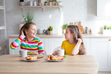 Portrait of two teenage beautiful smiling hipster girls in fashionable clothes. carefree children posing against the backdrop of the kitchen. Positive models have fun with sweets.