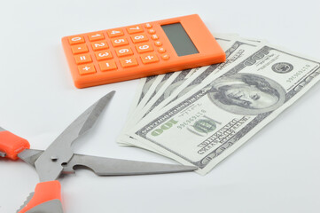 Selective focus of scissors, banknotes and calculator isolated on a white background. Devaluation concept.