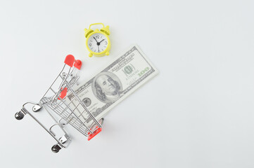 Top view of shopping cart, banknotes and clock isolated on a white background. Shopping concept.