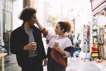 Cheerful tender couple drinking coffee in street