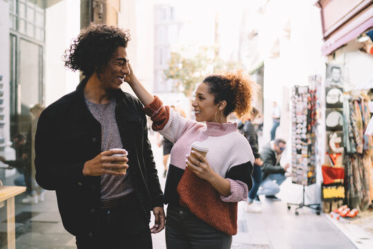 Cheerful tender couple drinking coffee in street