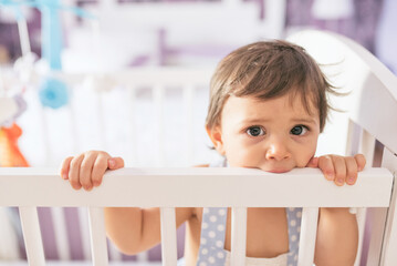 adorable toddler one year old in bedroom crib