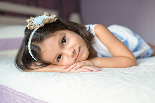 Beautiful little girl girl looks at camera in bed