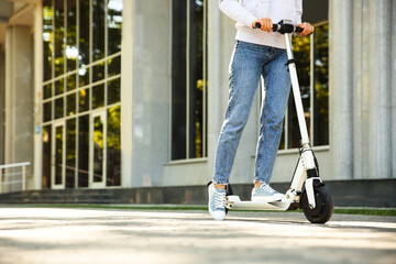 Woman riding electric kick scooter outdoors. Space for text