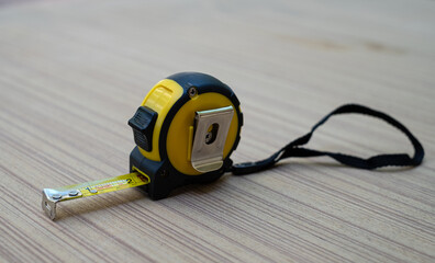 Yellow tape measure on wooden board