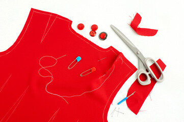 The process of sewing a dress from red fabric. Sew clothes using blueprints. Dress pattern on a white background. Tailoring and sewing items.