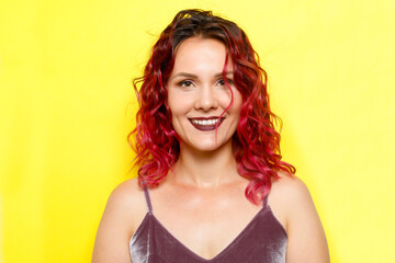 Indoor portrait of excited curly woman with trendy makeup. Ginger caucasian young lady smiling on yellow background.