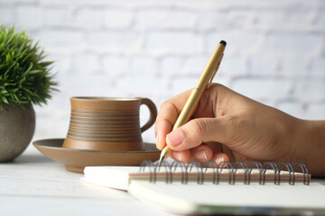 Close up of women hand writing on notepad.