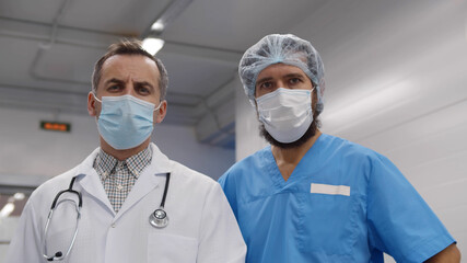 Fototapeta na wymiar Two doctors in protective medical mask and uniform stand in emergency department hall