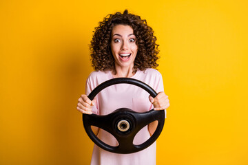 Photo portrait of amazed girl learning to drive keeping steering wheel staring smiling isolated on...