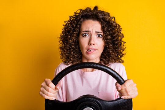 Photo portrait of stressed nervous female driver keeping steering wheel biting lip isolated on vibrant yellow color background