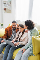 Fototapeta premium shocked hispanic girl watching film on laptop with family