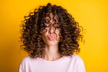 Headshot of girl with curly hairstyle wearing t-shirt send air kiss pouted lips isolated on vivid...