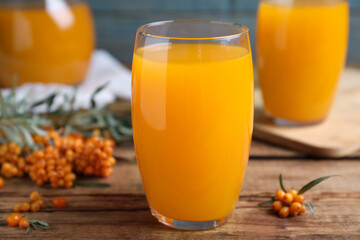 Sea buckthorn juice and fresh berries on wooden table, closeup