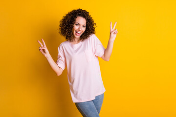 Photo portrait of girl showing two v-signs isolated on vivid yellow colored background