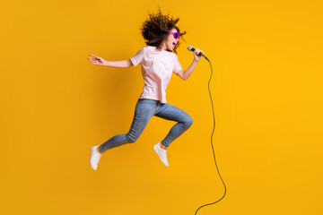 Photo portrait full body view profile of woman jumping up singing into mic isolated on vivid yellow...