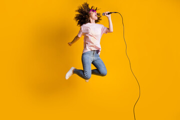 Photo portrait full body view of ecstatic woman jumping up singing into microphone isolated on...