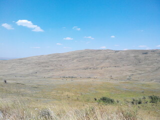 Obraz premium Light yellow hills under the sun. Stavropol region. Summer sunny day. Blue sky with rare clouds. Steppe with grass burnt out in the sun. Endless spaces.