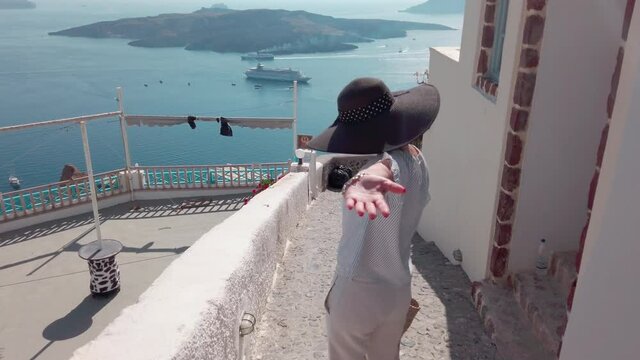 Beautivul woman with hat enjoy summer vacation walking on streets of Santorini