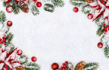 Christmas decoration. Frame of branches christmas tree, flowers of red poinsettia, brown natural spruce cones, red ball, red berries on snow with space for text. Top view, flat lay