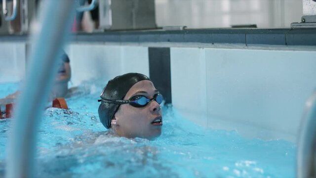 Young swimmer came first to the finish line and wins at the training. Slow motion shot of her happiness and celabration after winning. 