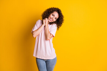 Photo of young cheerful curly brown hair woman hold hands together smile isolated over yellow color background