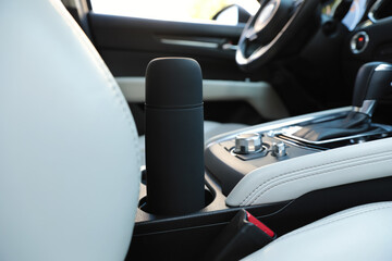 Black thermos in holder inside of car