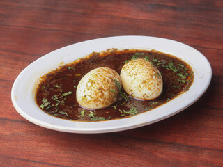 Anda Masala or Egg Curry is popular indian spicy food, served in a ceramic bowl over rustic wooden background. Selective focus