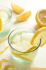 Soda water with lemon slices and ice cubes on white table