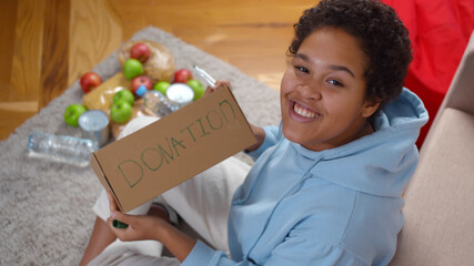 Top view of african woman writing donation in cardboard box for food packing