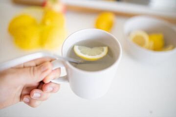 Hand holding a cup of lemon tea with a straw and lemon slice