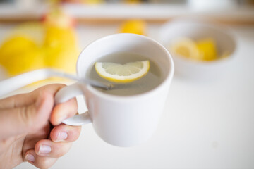 Hand holding a cup of lemon tea with a straw and lemon slice